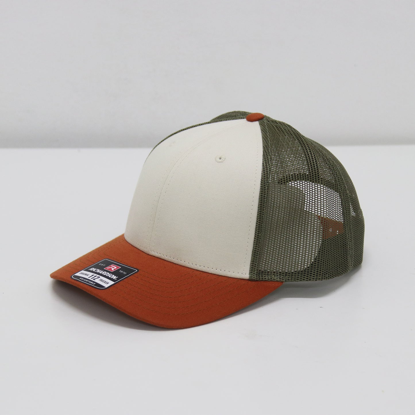 Trucker hat with a white front panel, green side panel, and brown bill on a white background