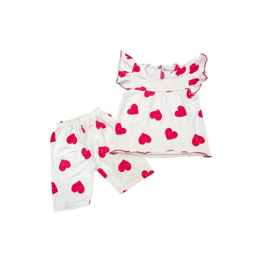 Children's outfit with white top and shorts featuring red heart patterns on a white background