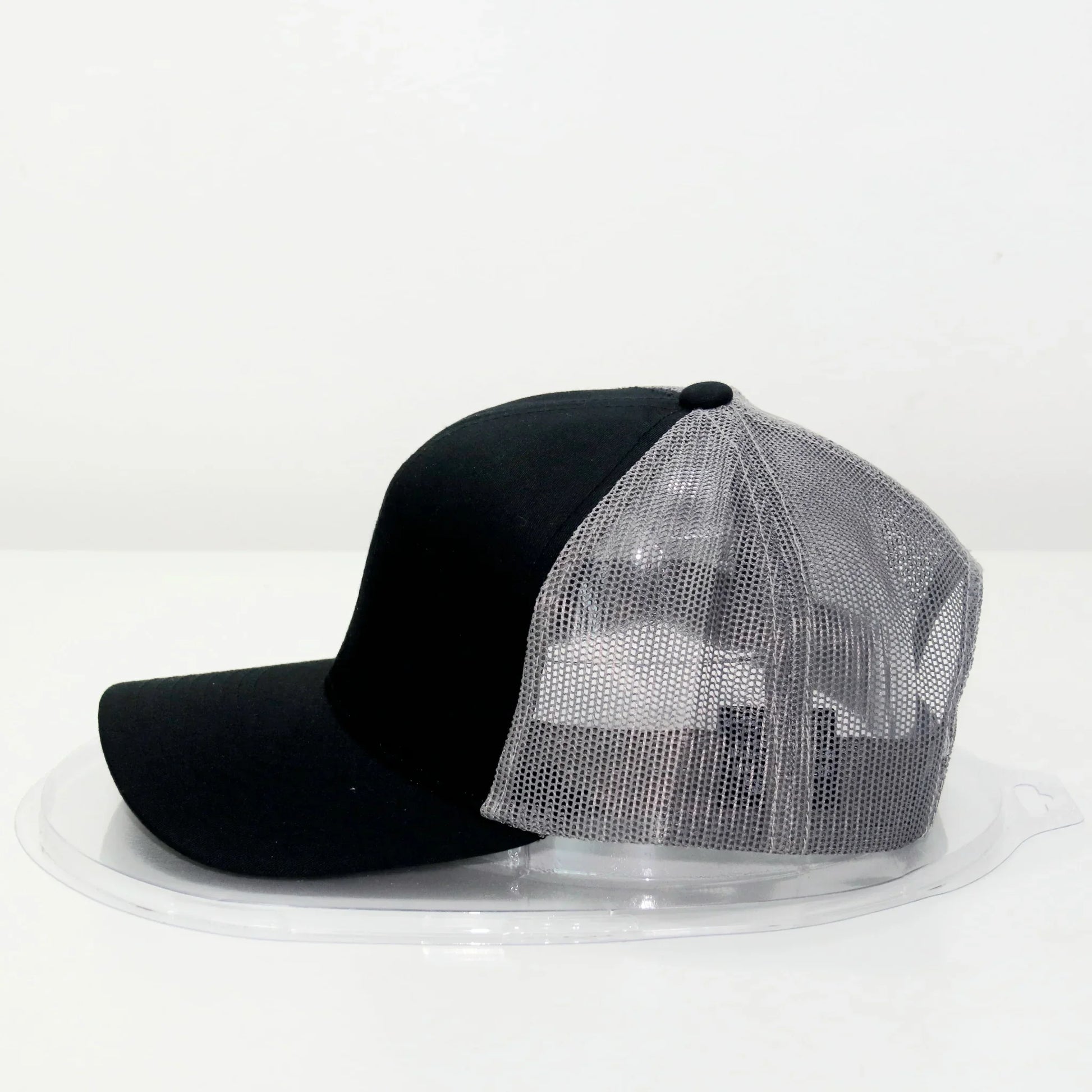 A black trucker cap with a curved brim, displayed on a white background.