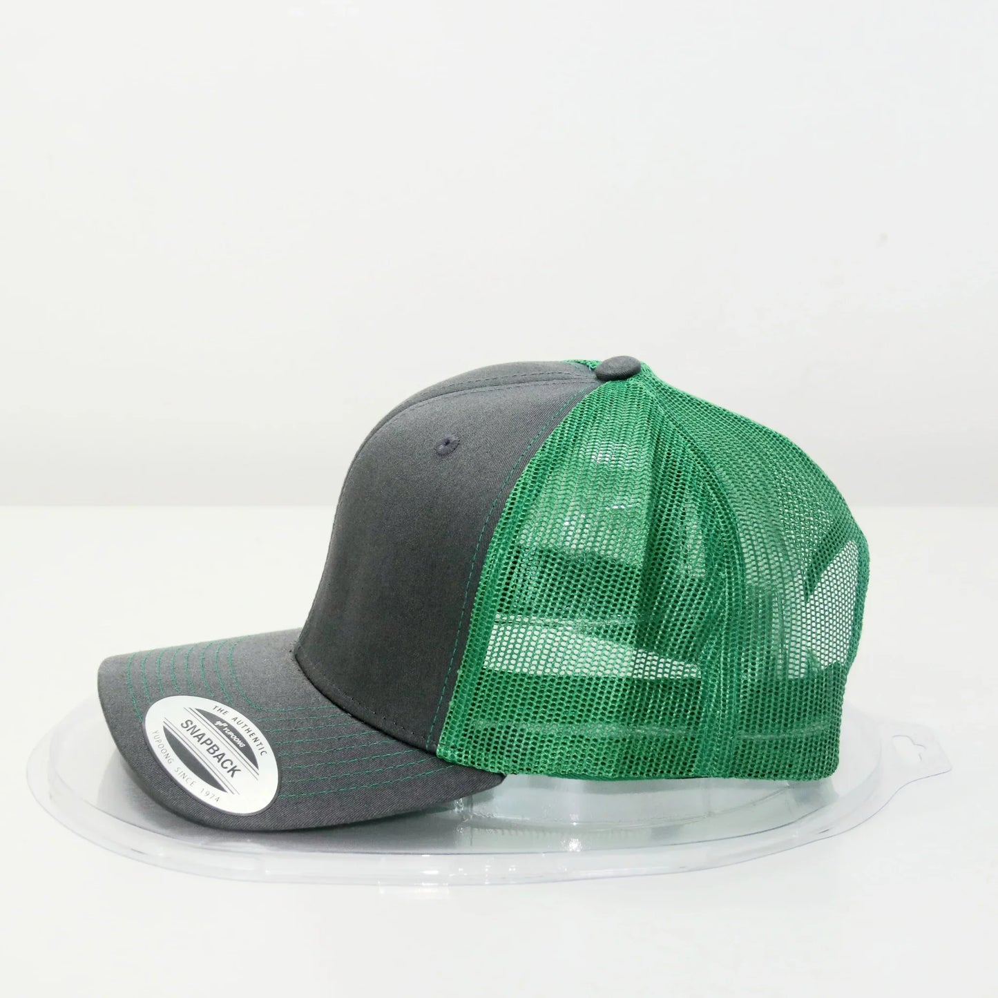 A trucker cap with a gray front panel and green mesh back, displayed on a white background.