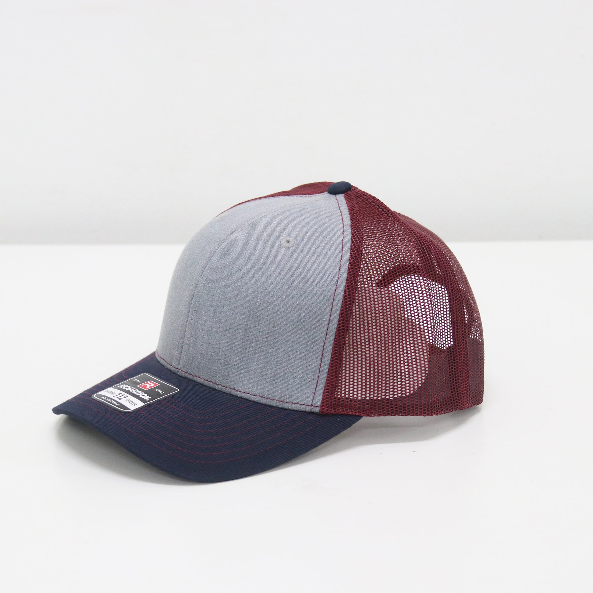 Trucker hat with gray front panel, maroon side panel, and navy bill on a white background