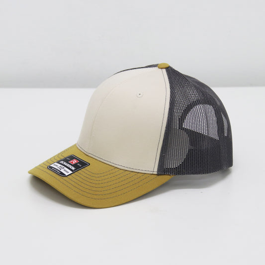 Trucker hat with a beige front panel, black mesh back, and mustard yellow brim on a white background