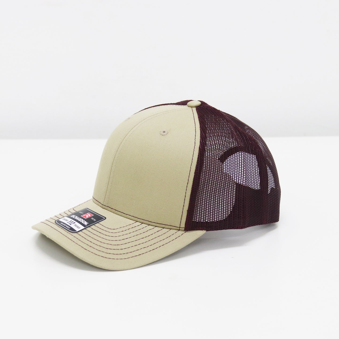 Beige and maroon baseball cap with mesh back on a white background