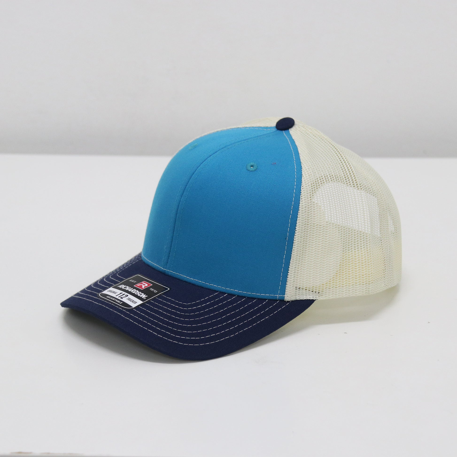Blue and white cap with mesh back on a white surface