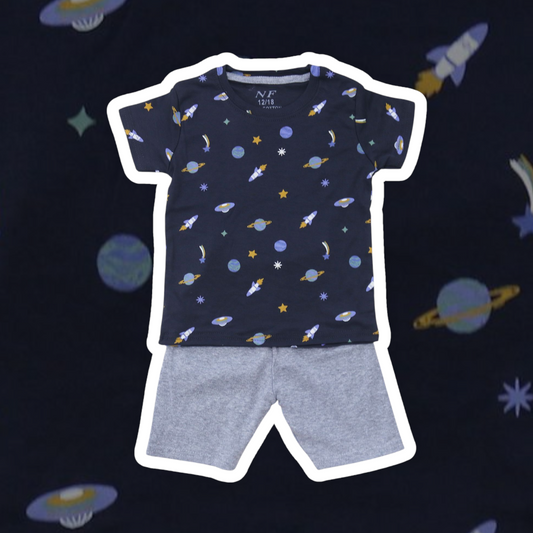Children's navy t-shirt with space-themed print and gray shorts on a dark background with space-themed illustrations.