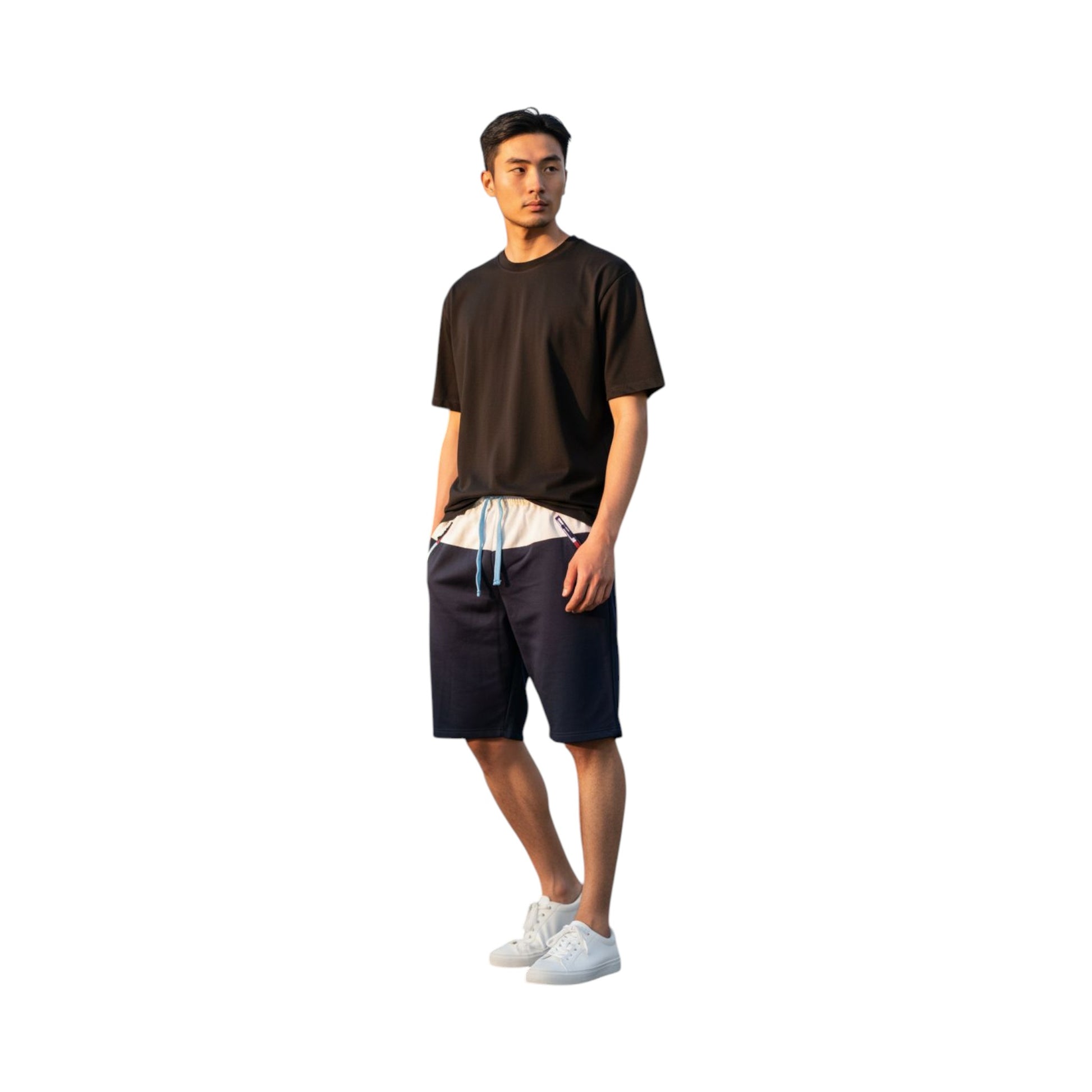 Man wearing a black t-shirt, navy shorts, and white sneakers on a white background